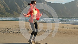 Stylish athletic woman goes in for sports on a wild beach at sunset