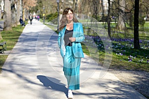Stylish attractive middle-aged woman in turquoise pants suit