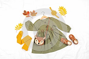 Stylish autumn set of child clothes. Green dress, brown bag, shoes and yellow tights, accessories for hair and autumn