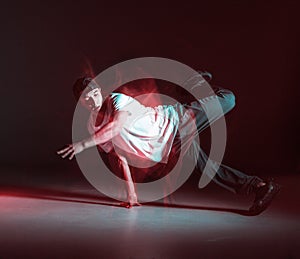 Stylish b-boy dancing hip-hop on the floor in studio in neon light. Dance school poster. Long exposure shot