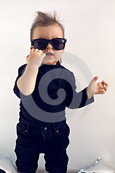 Stylish baby boy in black rocker clothes and sunglasses