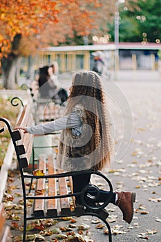 Stylish baby girl 4-5 year old wearing boots, fur coat with very long curly hair. View from the back. Autumn fall season