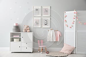 Stylish baby room with chest of drawers and cute pictures on wall