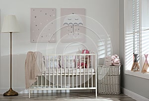 Stylish baby room with crib and cute pictures on wall