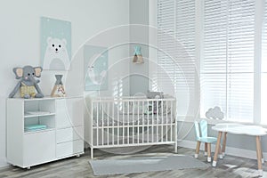 Stylish baby room with crib and cute pictures on wall