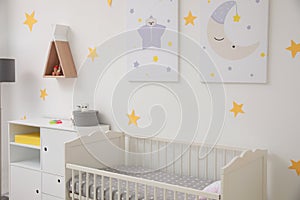 Stylish baby room with crib and decor elements