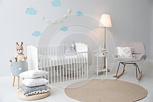 Stylish baby room with crib and rocking chair