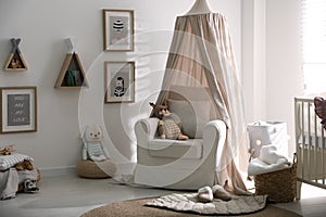 Stylish baby room interior with crib and armchair