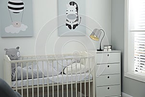 Stylish baby room interior with crib and chest of drawers