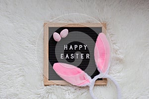 Stylish background with bunny ears and text Happy Easter on white fur background. Flat lay, top view, mockup, overhead