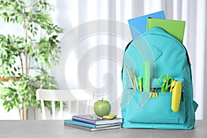 Stylish backpack with different school stationery on table. Space for text photo