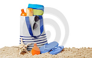 Stylish bag with beach accessories on sand against white background