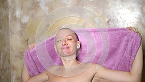 Stylish bald woman wipes her head with a towel after a shower. adventures of strange people , humor.