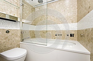 Stylish bathroom with large designer bathtub and mosaic tiled wa