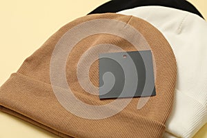 Stylish beanies on beige background, close up