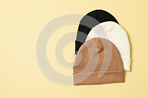 Stylish beanies on beige background, top view