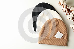 Stylish beanies and cotton on white background