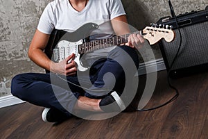 Stylish bearded guy with guitar against concrete wall