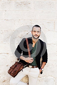 Stylish bearded man standing against of white wall and looking at camera