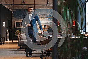 Stylish bearded man in a suit standing in modern office