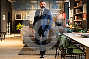 Stylish bearded man in a suit standing in modern office