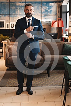 Stylish bearded man in a suit standing in modern office