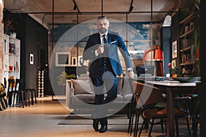 Stylish bearded man in a suit standing in modern office