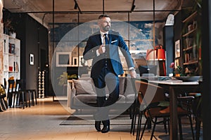 Stylish bearded man in a suit standing in modern office