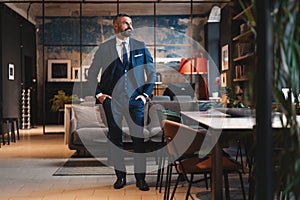 Stylish bearded man in a suit standing in modern office