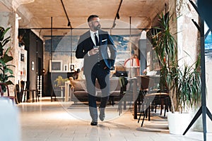 Stylish bearded man in a suit standing in modern office