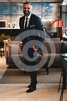 Stylish bearded man in a suit standing in modern office