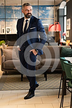 Stylish bearded man in a suit standing in modern office