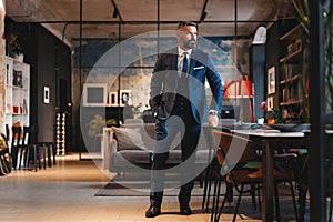 Stylish bearded man in a suit standing in modern office