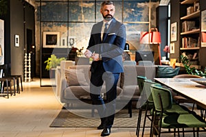 Stylish bearded man in a suit standing in modern office