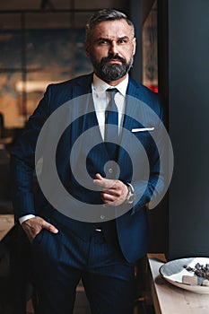 Stylish bearded man in a suit standing in modern office