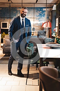 Stylish bearded man in a suit standing in modern office