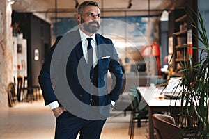 Stylish bearded man in a suit standing in modern office