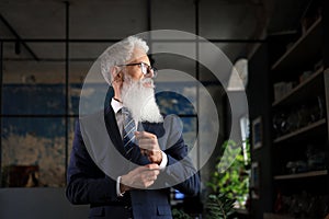 Stylish bearded man in a suit standing in modern office.