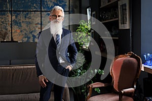 Stylish bearded man in a suit standing in modern office.