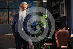 Stylish bearded man in a suit standing in modern office.