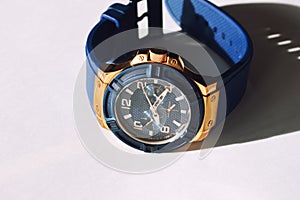 Stylish blue wrist watch on a white background. Round dial in blue and gold colors.