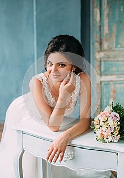 Stylish, beautiful bride in a luxurious dress posing against the backdrop of a rich interior. Fine Art Wedding