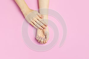 Stylish beautiful gentle manicure. Hands of young woman on pink background top view flat lay copy space. Natural nails