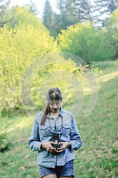 Stylish beautiful girl hipster with analog photo camera in spri