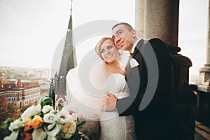 Stylish beautiful wedding couple kissing and hugging on background panoramic view of the old town