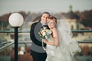 Stylish beautiful wedding couple kissing and hugging on background panoramic view of the old town