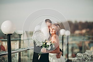 Stylish beautiful wedding couple kissing and hugging on background panoramic view of the old town