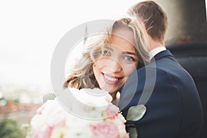 Stylish beautiful wedding couple kissing and hugging on background panoramic view of the old town