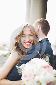 Stylish beautiful wedding couple kissing and hugging on background panoramic view of the old town