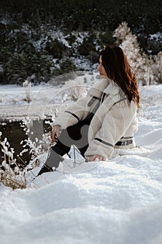 Stylish and beautiful woman seated gracefully on snow